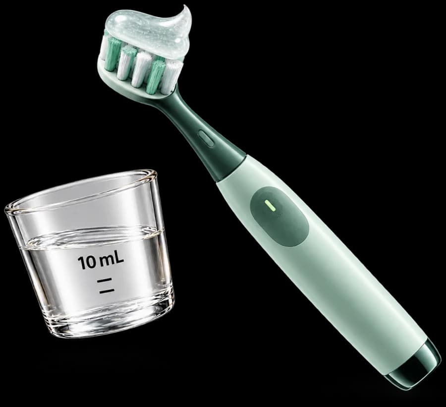 A toothbrush with gel beside a rinse measuring cup