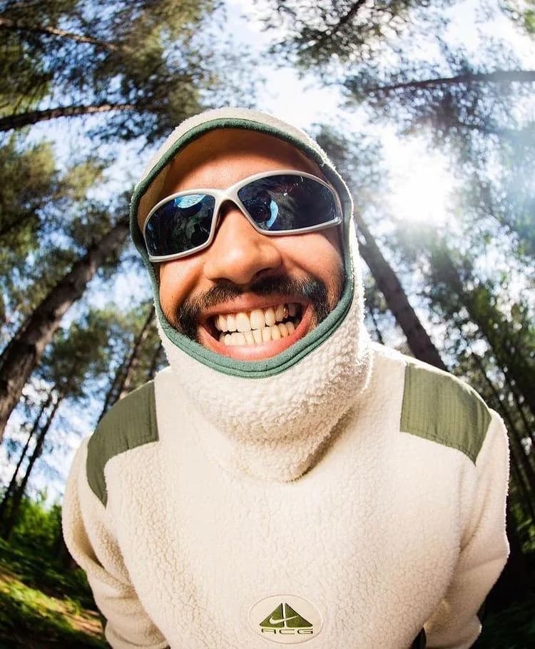 Smiling hiker wearing sunglasses and a fleece hood in a forest