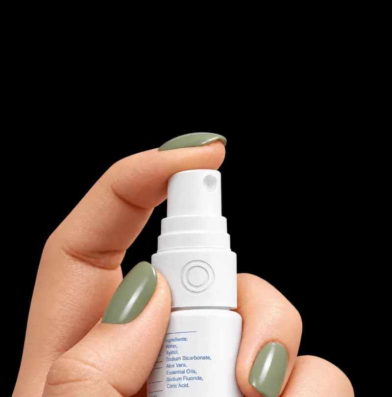 Hand holding an illustrative white ONEORAL oral spray bottle