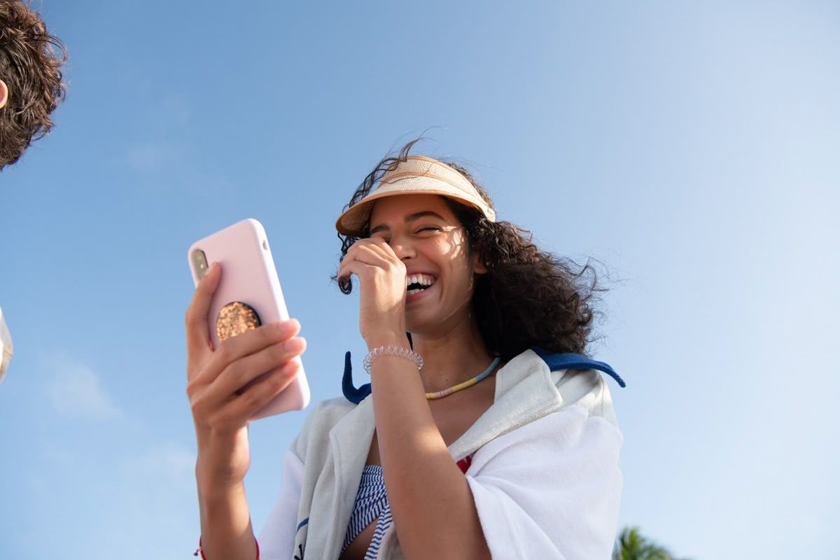 Woman smiling with phone outdoors